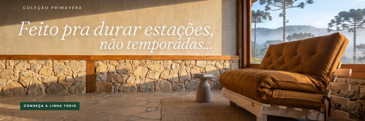 Sofá-cama Tokio em sarja caramelo numa sala de casa na serra, com araucárias e névoa vistas pela janela. Texto: “O aconchego tem seu lugar”. Botão “Conhecer o Tokio” leva à página do produto.